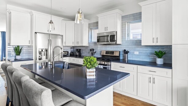 A modern kitchen with white cabinets, a central island, stainless steel appliances, and pendant lighting. - Stunning 6 BR Home * Chicago * Centrally Located (Chicago)