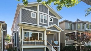 A two-story residential building with a front porch, a garage, and a staircase leading to the second floor. - Stunning 6 BR Home * Chicago * Centrally Located (Chicago)