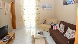 A living room with a beige sofa, a brown couch, a glass coffee table, and a flat-screen TV. - City House. Life in the center. (Campofelice di Roccella)