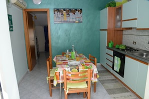 A compact kitchen with a dining table set for four, a sink, and a stove.