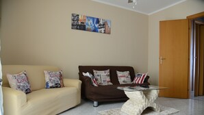 A living room with a beige sofa, a brown sofa, and a glass coffee table. - City House. Life in the center. (Campofelice di Roccella)