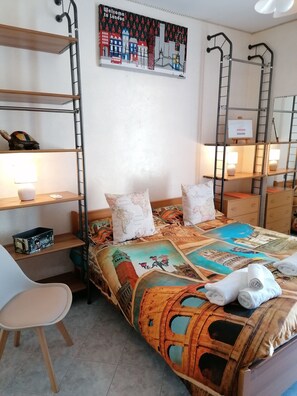 A bedroom with a bed, shelves, a desk, and a chair.