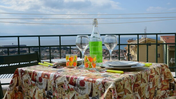 A table set with plates, glasses, and a bottle, overlooking a scenic view. - City House. Life in the center. (Campofelice di Roccella)