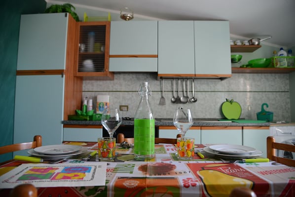 A kitchen with light blue cabinets, a green bottle, and a table set with plates and glasses.