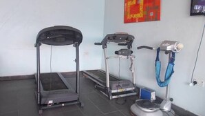 Una habitación con cinta de correr, bicicleta estática y máquina de pesas.