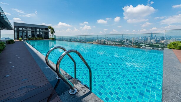 A rooftop infinity pool with a city view, a wooden deck, and a glass-enclosed structure. - Ekocheras (Kuala Lumpur)