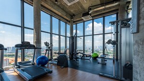 A gym with a treadmill, exercise balls, and weight machines, featuring large windows and a city view. - Ekocheras (Kuala Lumpur)