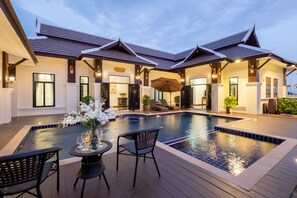 Une villa moderne dotée d’une piscine, d’un espace salon extérieur et d’un patio couvert.