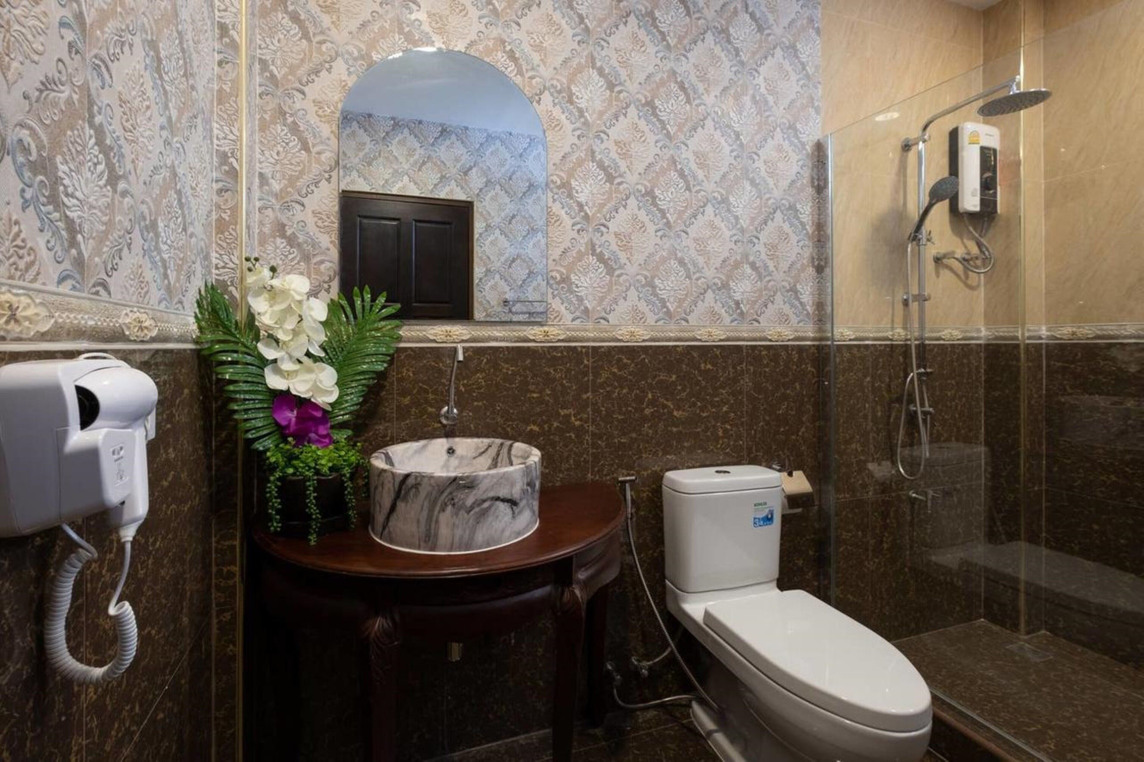 A bathroom with a marble sink, a toilet, a hairdryer, and a shower.