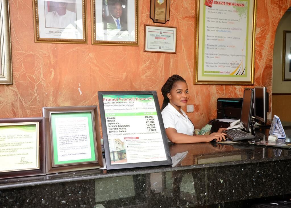 A hotel reception desk with framed certificates and a promotional sign.