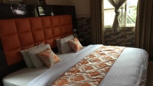 A hotel room with a large bed, a headboard, and a window with curtains. - Terrace Green Hotels (Lagos)