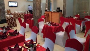 A banquet hall with round tables, red and white tablecloths, and matching chair sashes. - Terrace Green Hotels (Lagos)