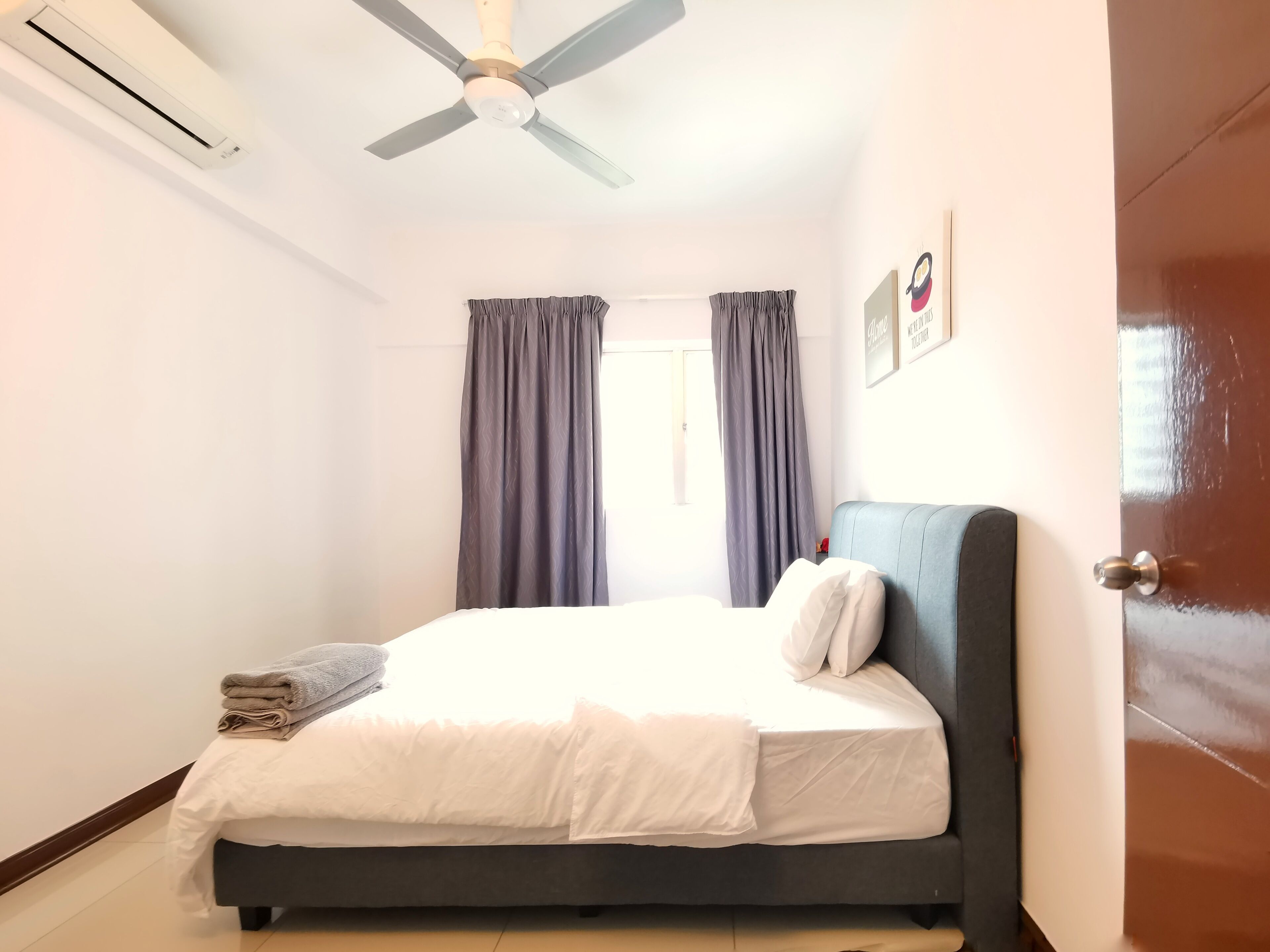 A bedroom with a bed, a ceiling fan, and a door.