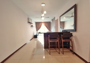 Relax in a stylish room with a large mirror, ceiling fan, and bar area with two chairs.