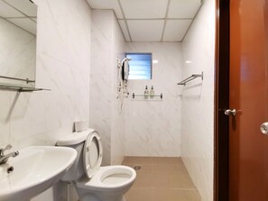 Et lille badeværelse med toilet, håndvask og brusebad.