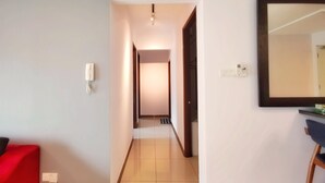 Un pasillo con un sofá rojo, un teléfono y un espejo en la pared.