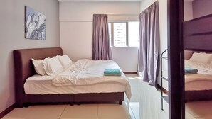 Una habitación de hotel con cama, ventilador de techo, ventana con cortinas y un cuadro de paisaje urbano en la pared.
