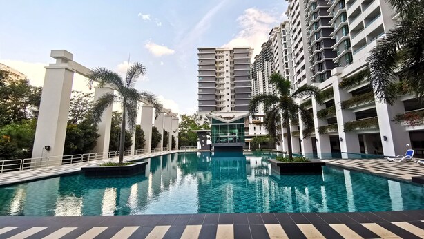 Un hotel moderno con piscina central, edificios altos y palmeras.