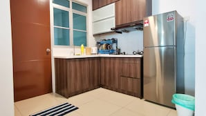 Una cocina compacta con armarios de madera, un refrigerador de acero inoxidable y un ventanal con vidrio esmerilado.