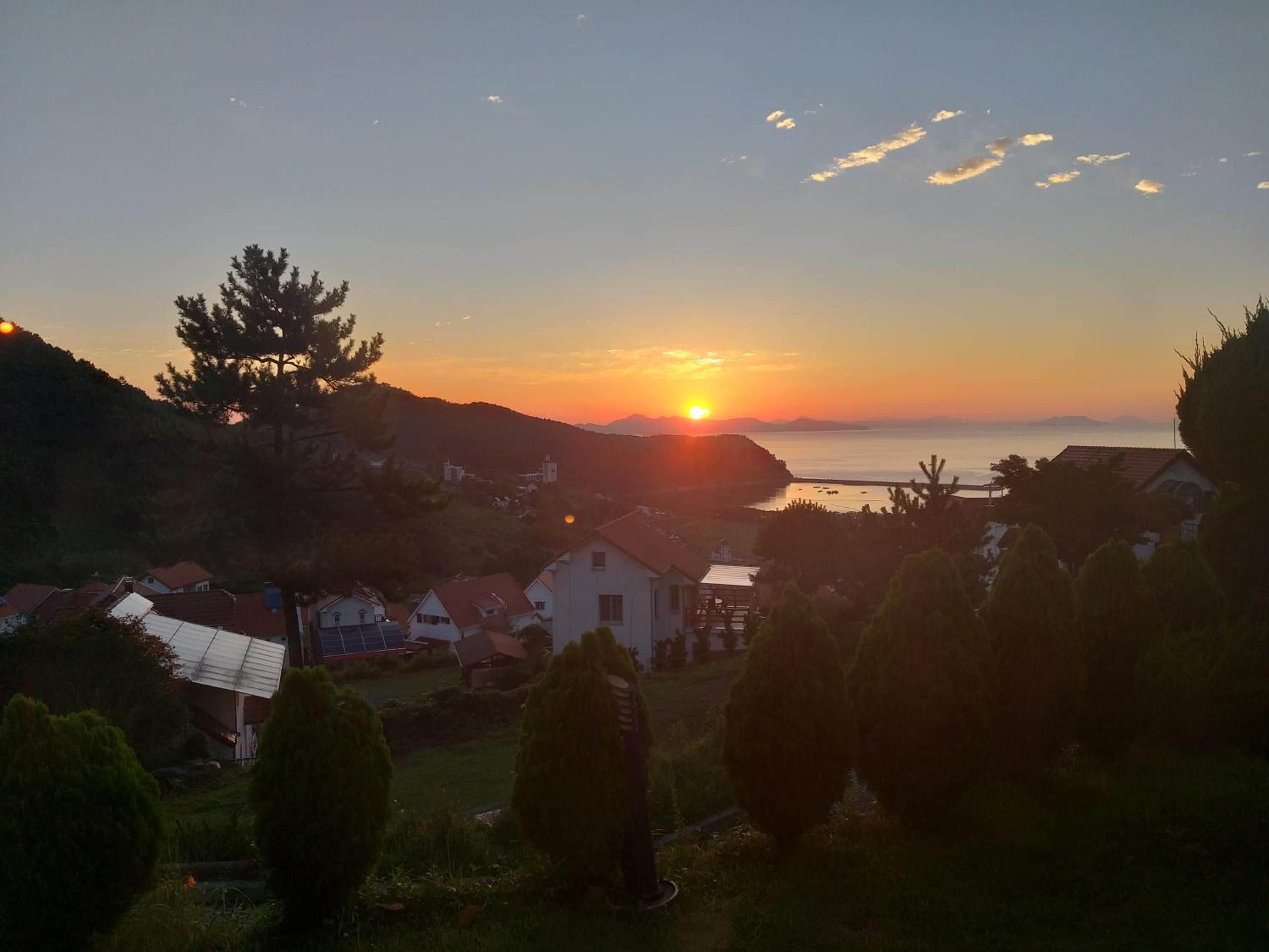 Vista al atardecer sobre una zona costera con casas y árboles.