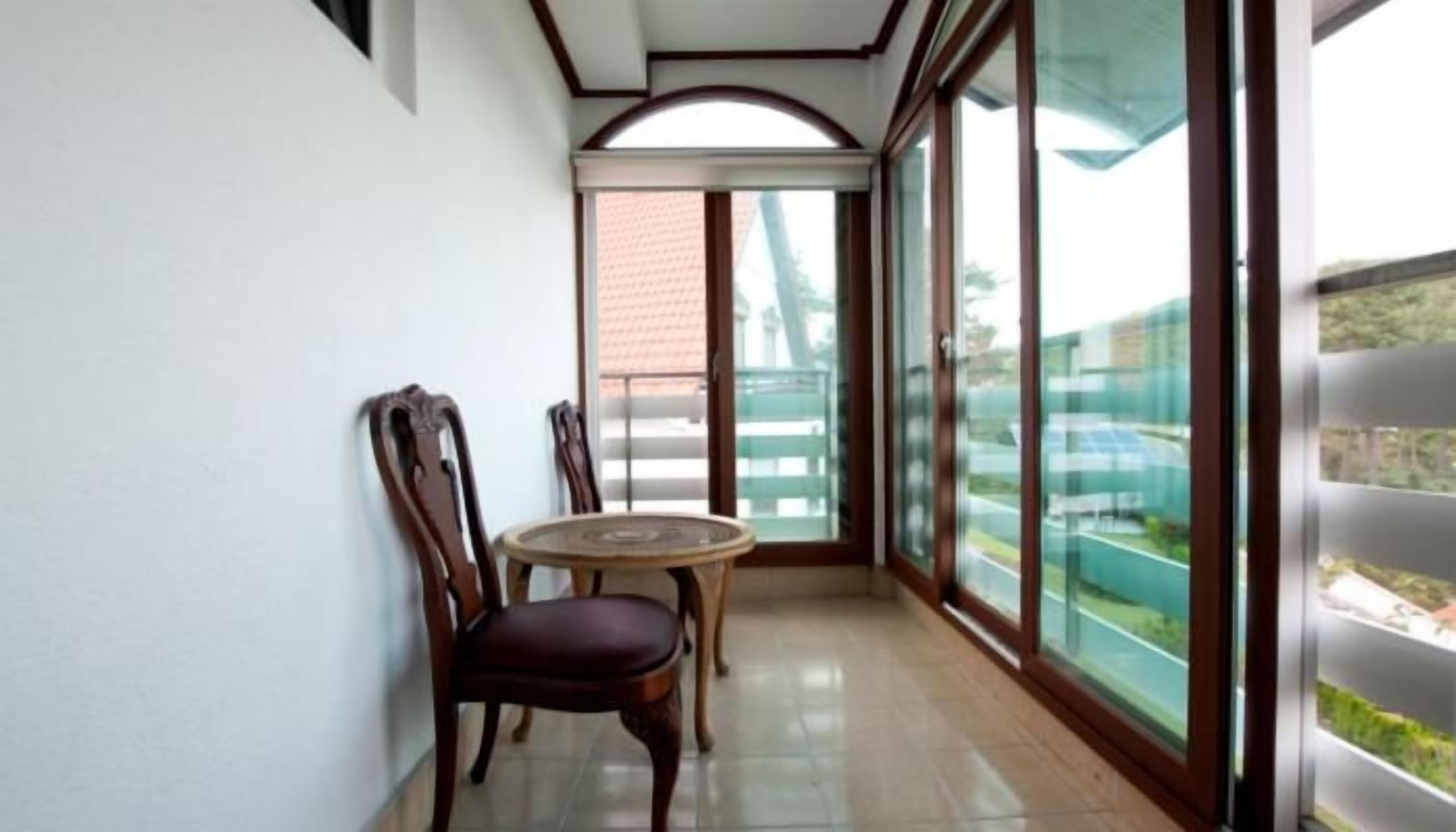 A balcony with a table and chairs, large windows, and a view of the outside.