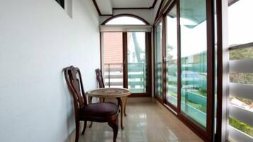 A balcony with a table and chairs, large windows, and a view of the outside.