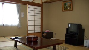 A traditional Japanese room with tatami flooring, a low table, a television, and a sliding door. - Hotel Khuls Shigakogen (Yamanouchi)