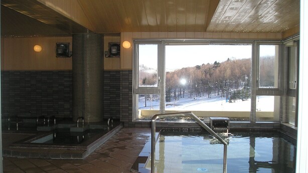 A spa area with a hot tub and a view of a snowy landscape through large windows. - Hotel Khuls Shigakogen (Yamanouchi)