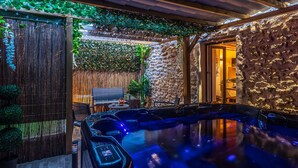 Zona de hidromasaje con pared de piedra y pérgola de madera.