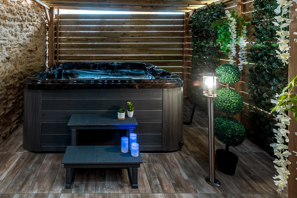 Ein Wellnessbereich mit Whirlpool, Holzbänken und Topfpflanzen.