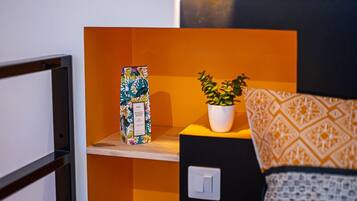 Een gezellige kamer met een bed, een plankje met een plant erop en een wandlamp.