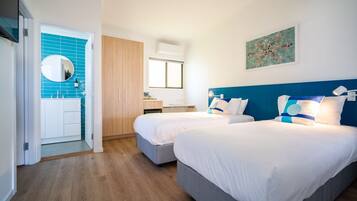 Una habitación de hotel con dos camas, un armario de madera, un baño con azulejos azules y un cuadro en la pared.