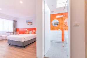 Een moderne hotelkamer met een bed, een bureau en uitzicht op de badkamer.