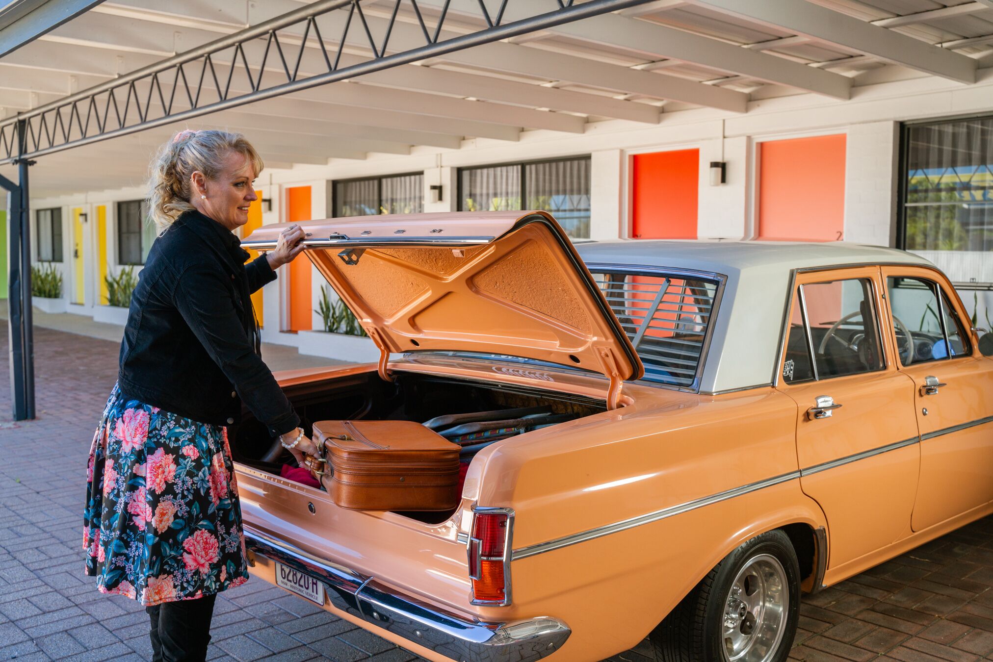 A vintage car with its trunk open, revealing luggage inside.