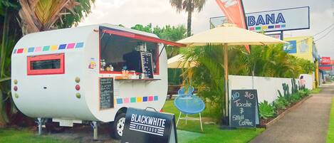 A food truck with a sign for Black & White Espresso Coffee, a 'BANA' sign, and a 'tiles' sign in the background.