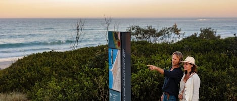 Una pareja señala un mapa cerca de una playa con vistas al océano.