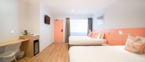 Habitación de hotel con dos camas, un escritorio, una silla y un televisor.