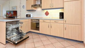 A kitchen with wooden cabinets, a microwave, a dishwasher, and a tiled backsplash.