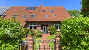 A brick house with a tiled roof, solar panels, a front gate, and a well-maintained garden.