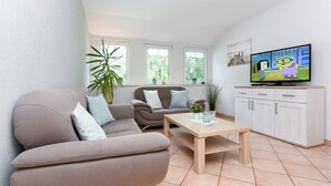 A modern living room with a beige sofa, a wooden coffee table, and a television on a cabinet.