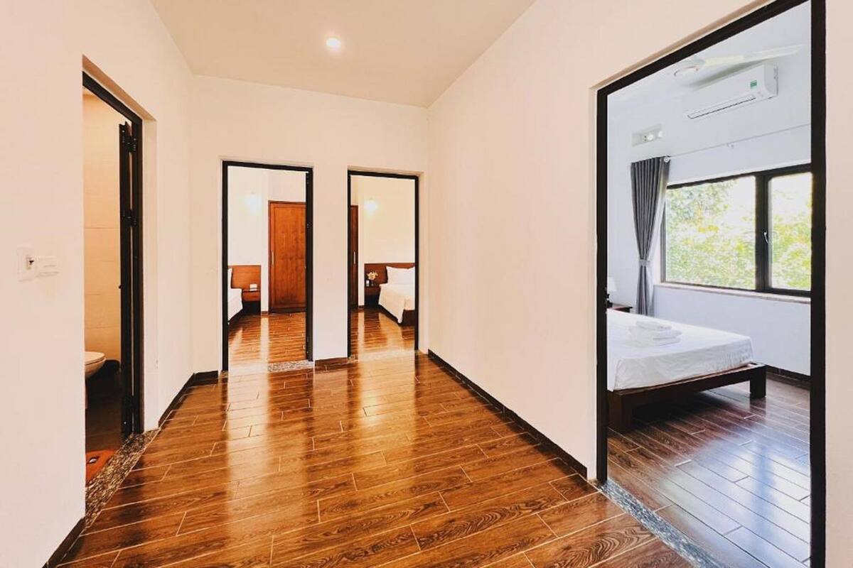 Habitación de hotel con piso de madera, una cama, un ventanal con cortinas y un equipo de aire acondicionado.