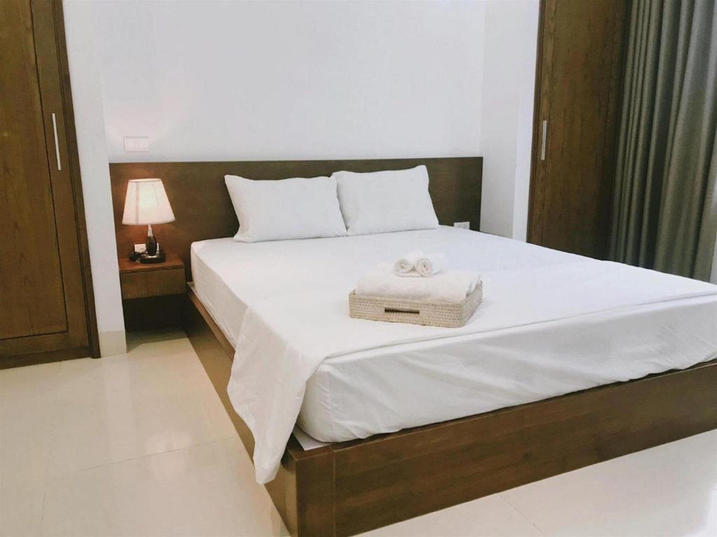 A neatly made bed with white linens and a folded towel on the side.