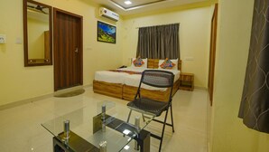 A bedroom with a bed, a chair, a desk, a ceiling fan, and an air conditioner. - Zenith Residency (Bengaluru)