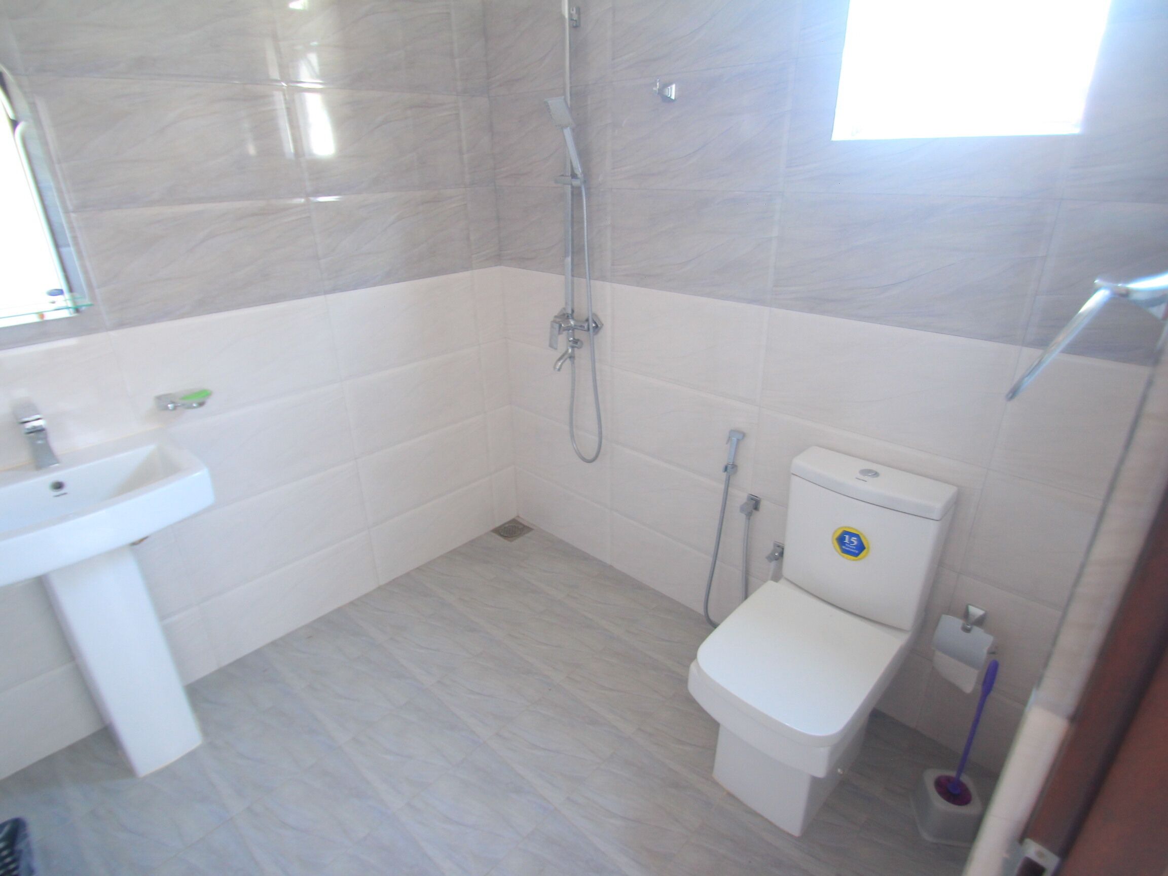 Une petite salle de bain moderne avec un lavabo, des toilettes et une douche, le tout de couleur blanche.