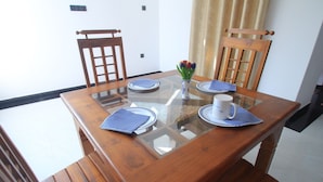 Een eettafel met een glazen blad, omringd door houten stoelen.