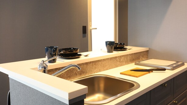 A modern kitchen with a stainless steel sink, a countertop with a cutting board and knife, and a mirror above the sink. - Moto Hotel (Tokyo)