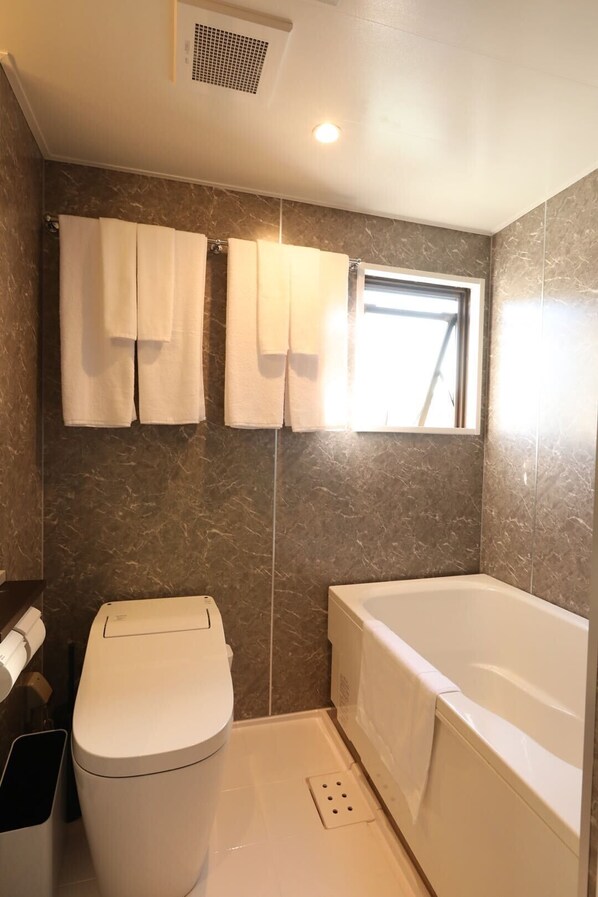 A bathroom with a toilet, bathtub, and a window. - Moto Hotel (Tokyo)