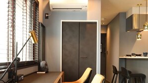 A modern kitchen with dark wood flooring, a built-in bench, and a window with blinds. - Moto Hotel (Tokyo)