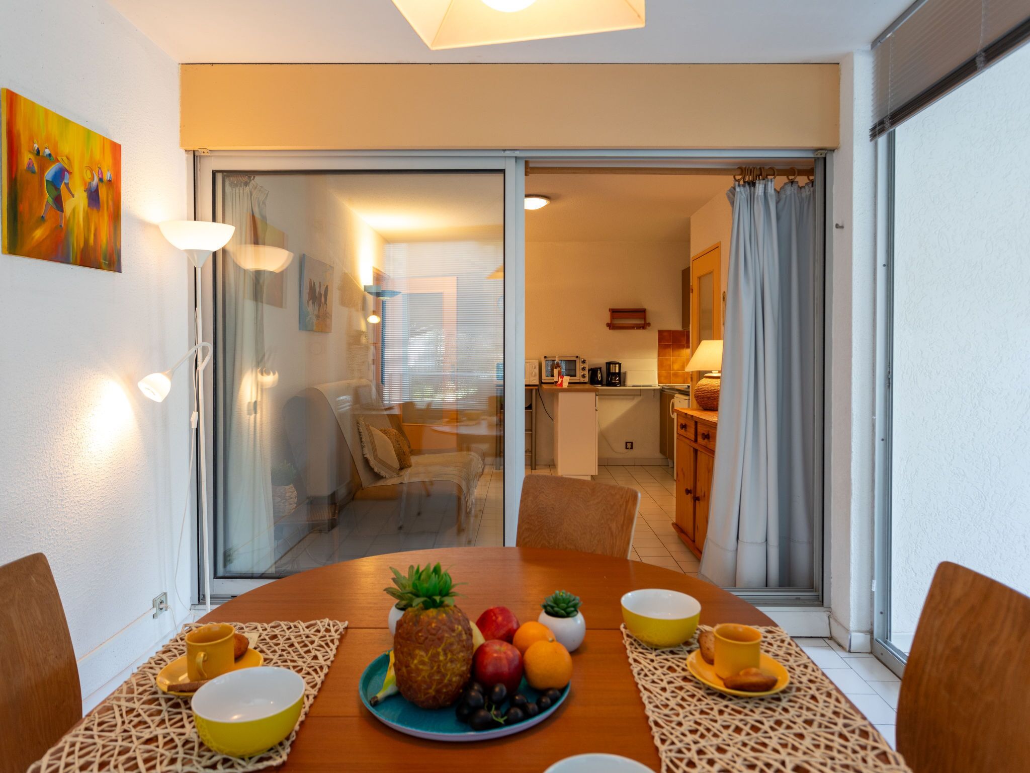 Een eetgedeelte met een houten tafel gedekt voor het ontbijt, met fruit en kommen.