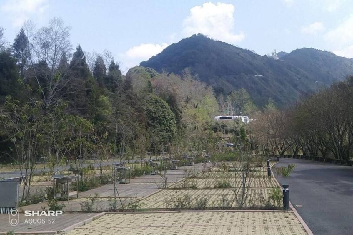 A parking area with a mountain in the background, a building with a sloped roof, and a paved walkway.